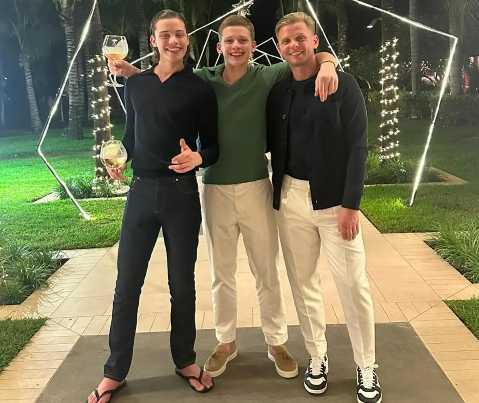 Three men posing together outdoors at night.