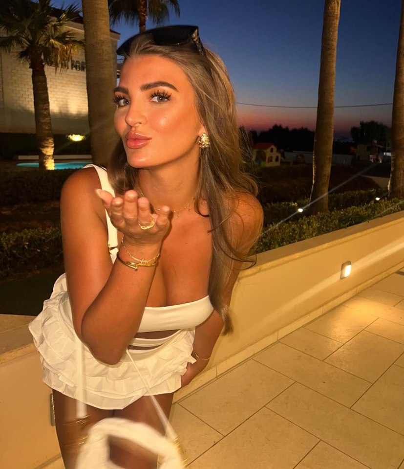 Woman blowing a kiss while wearing a white outfit.