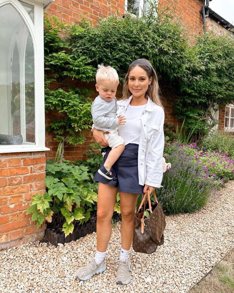 Woman holding a toddler in front of a brick house.