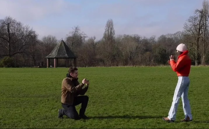 A man proposing to a woman in a park.