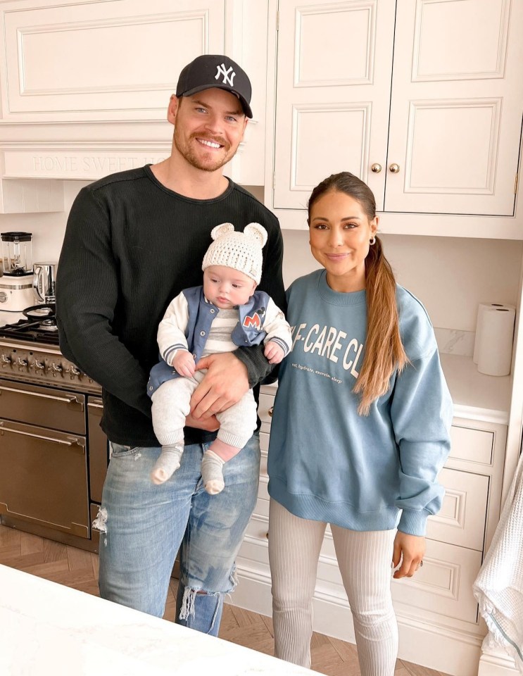 a man wearing a ny hat is holding a baby