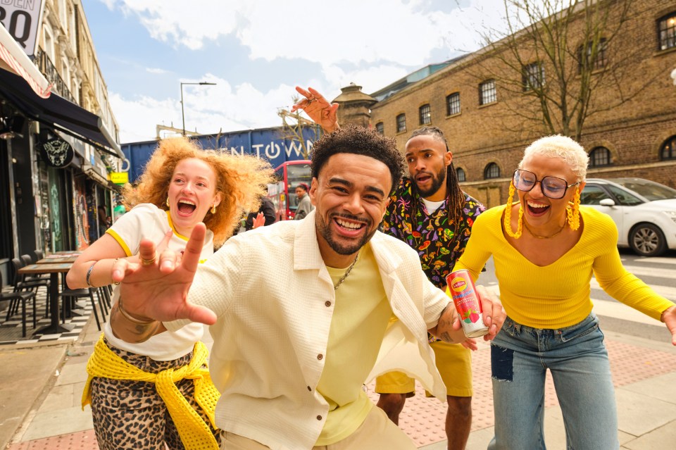 A group of friends joyfully holding a Lipton Kombucha can.