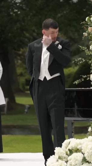 A groom wiping away tears at his wedding.