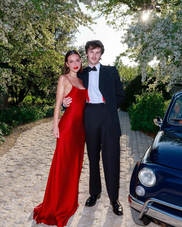 Couple posing for a photo.  The woman wears a red dress; the man wears a tuxedo.