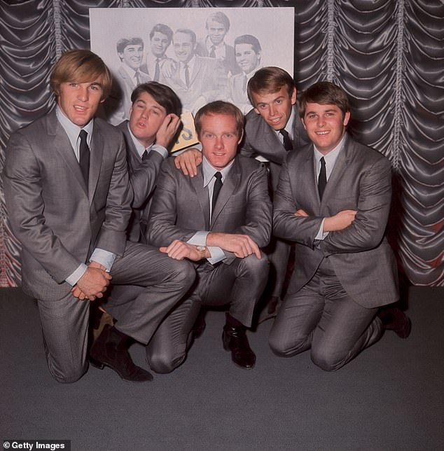 Al Jardine is speaking out following the death of his longtime confidante and collaborator Brian Wilson at 82. The Beach Boys pose in front of an earlier group portrait in 1964 in London. (L-R) Dennis Wilson (1944 - 1983), Brian Wilson, Mike Love, Al Jardine and Carl Wilson (1946 - 1998)