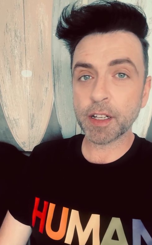 Man wearing a black t-shirt that says "HUMAN" in rainbow colors.