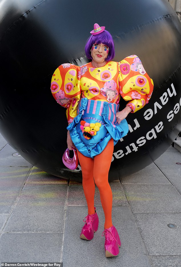 The cross-dressing potter, 65, was a riot of colour in a purple wig and an orange and yellow jumper featuring exaggerated puff sleeves