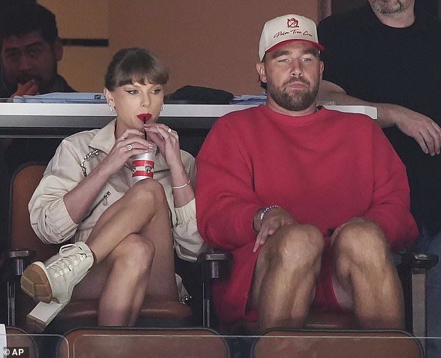 Taylor sipped on a canned beverage as she watched the game with Travis by her side