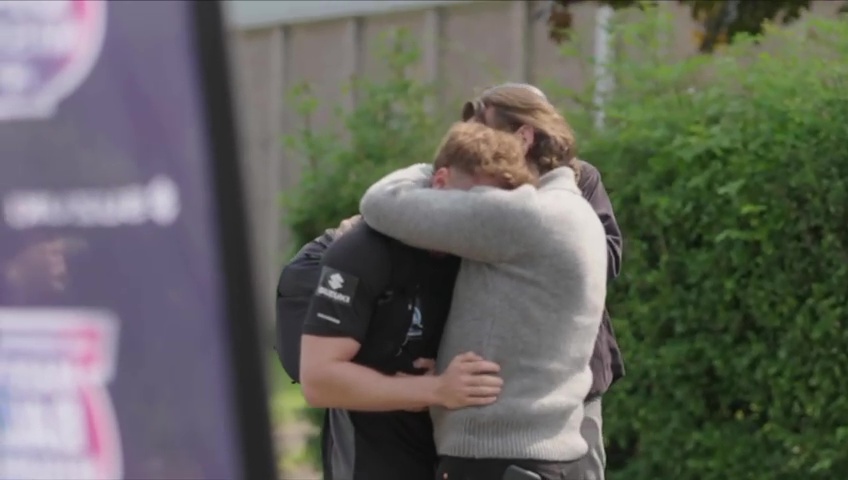 Sam Thompson embraced by another person, appearing emotional.