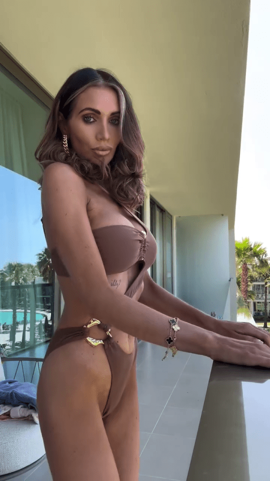 Amy Childs in a brown cutout swimsuit on a balcony.