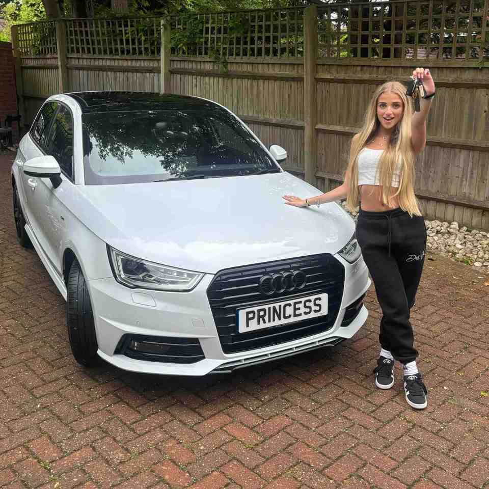 Woman holding car keys in front of her new white Audi with a "Princess" license plate.