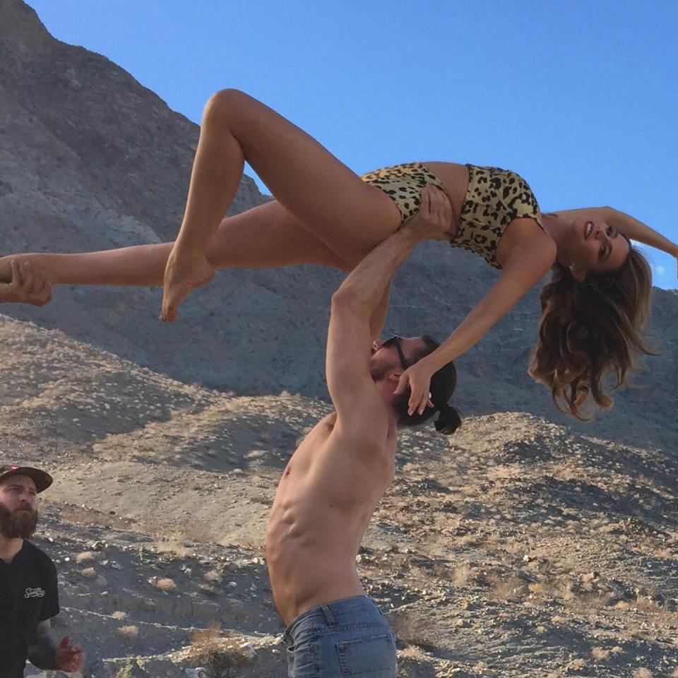 Behind-the-scenes photo of Sofia Vergara being lifted by a man during a photoshoot.