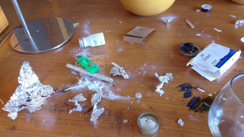 Hotel room surface littered with white powder, foil, and debris.