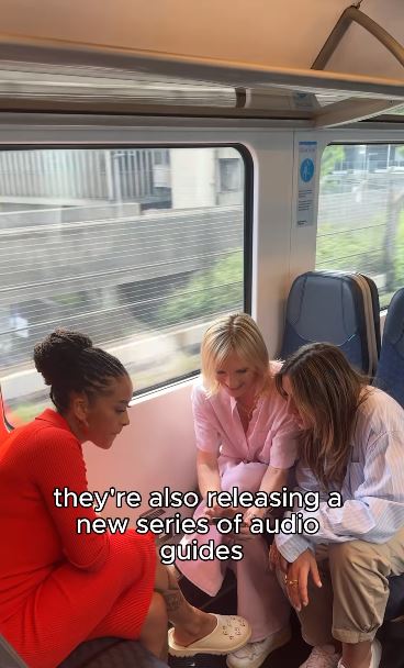 Three women on a train looking at a phone.