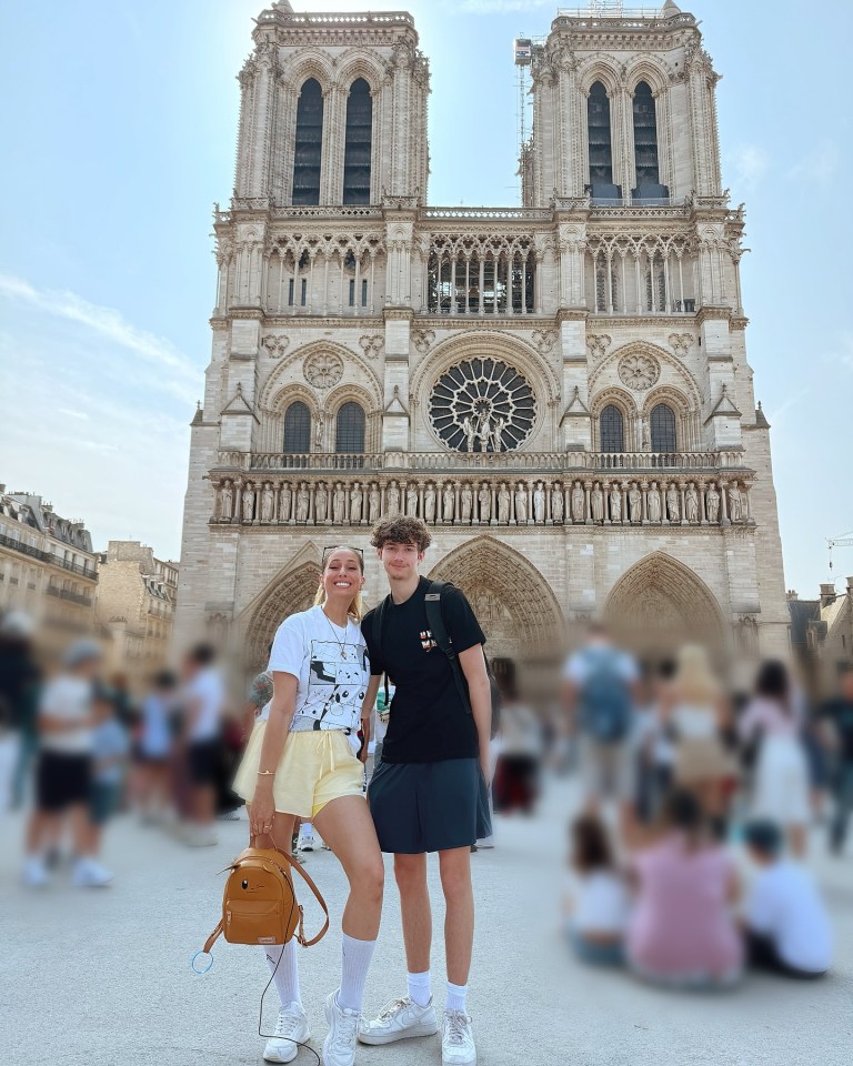 Two people posing in front of Notre Dame Cathedral.