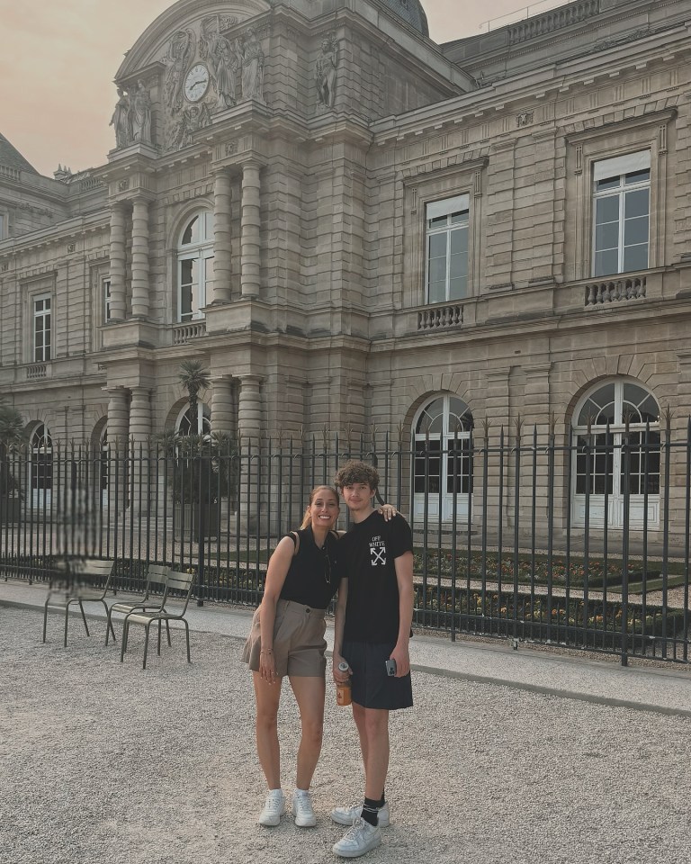 Two people posing in front of a large stone building.
