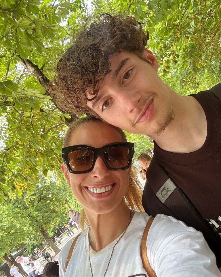 Selfie of a woman and a young man under a tree.