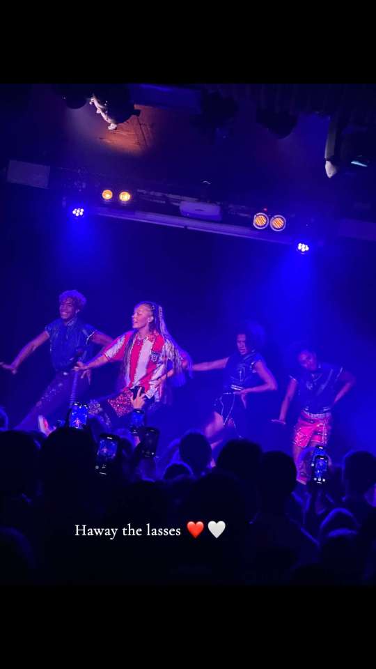 JoJo Siwa performing on stage with backup dancers.