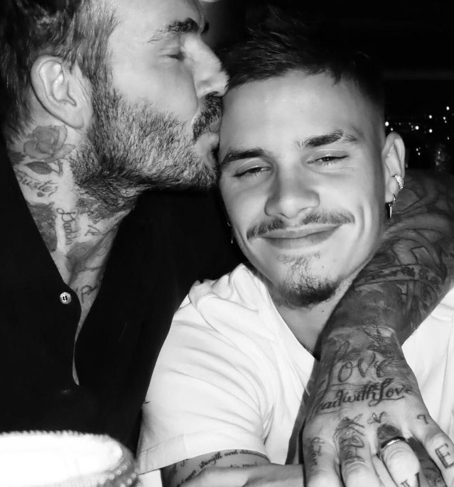 Black and white photo of David Beckham kissing his son on the forehead.