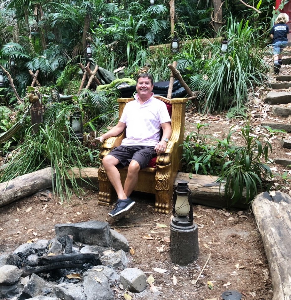 Man sitting on a throne in a jungle setting.