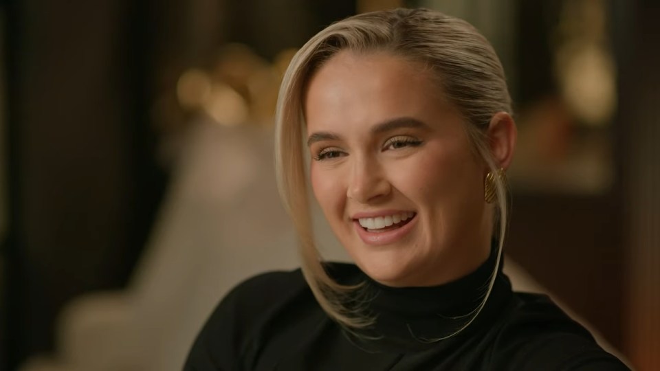 Molly-Mae Hague smiling in a black turtleneck.