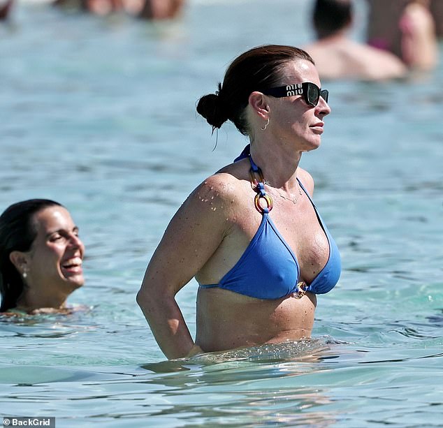 She accessorised perfectly for the sunny day with a pair of designer Miu Miu shades and swept back her brunette tresses while topping up her tan