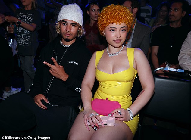 The singer later had an outfit change once inside the venue and donned a vibrant yellow minidress along with flashy silver jewelry; seen above with RiotUSA