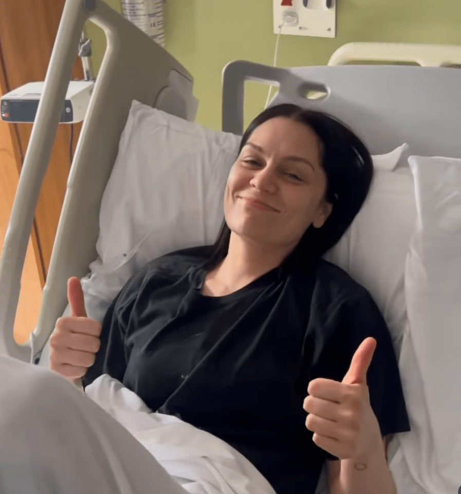 Woman in hospital bed giving thumbs up.