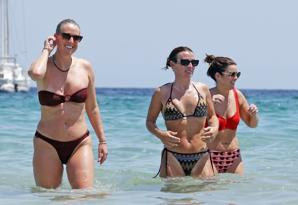 Three women in bikinis in the ocean.