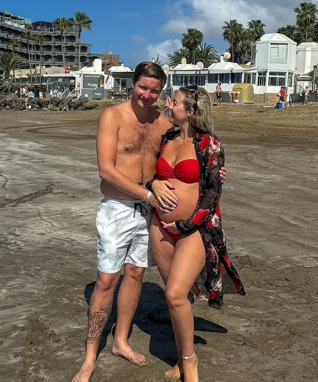 Pregnant woman and her partner on a beach.