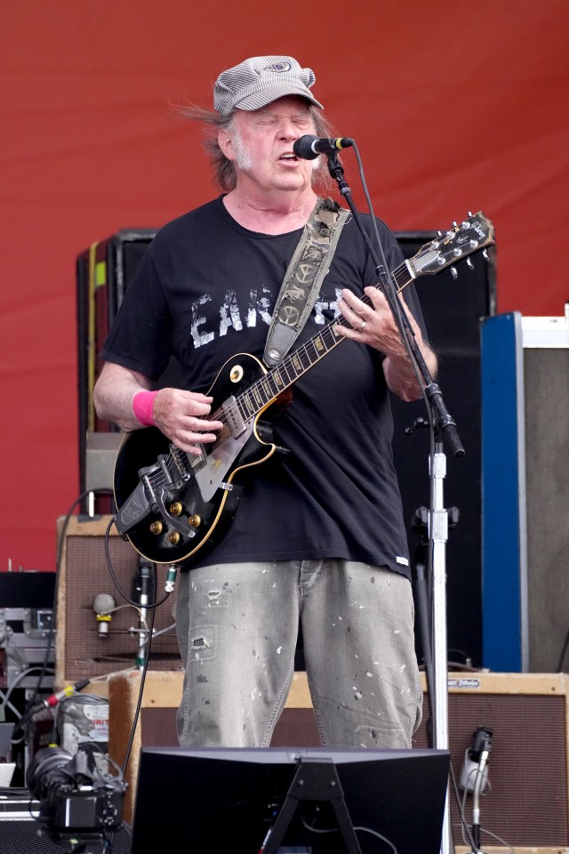 Neil Young of Crazy Horse performing onstage with a guitar.