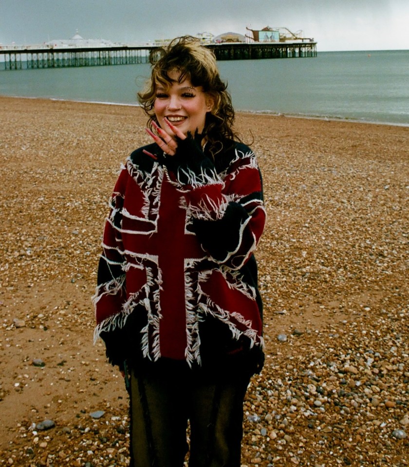 Woman wearing a Union Jack sweater on a beach.