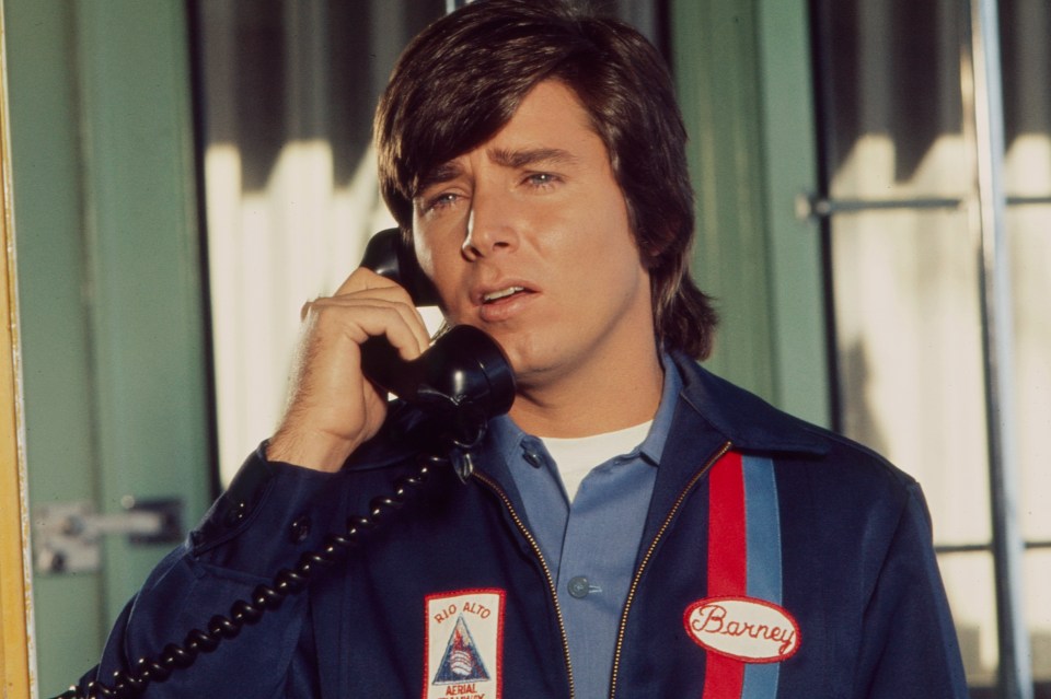 Man in a uniform jacket on a phone.