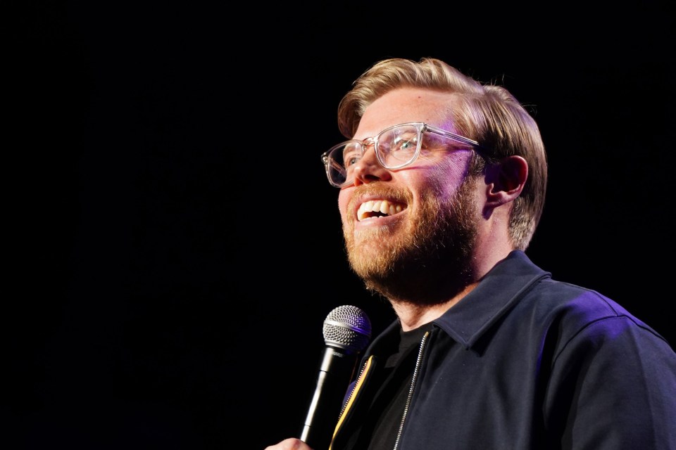 Rob Beckett on stage at a comedy show.