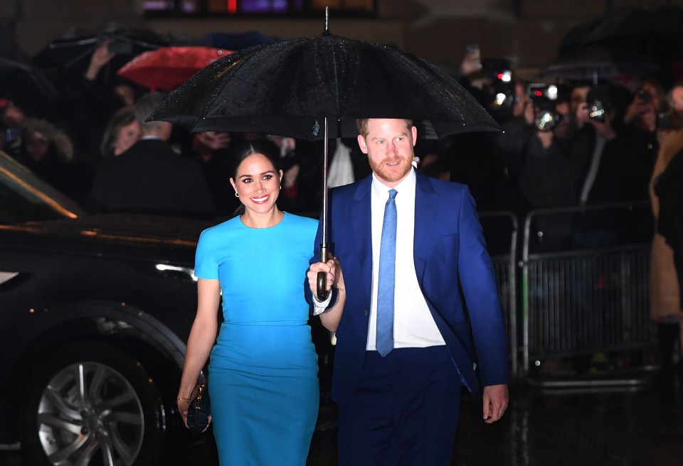 Prince Harry and Meghan Markle under an umbrella.