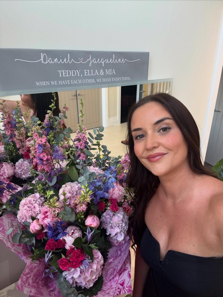 Woman smiling with large bouquet of flowers.