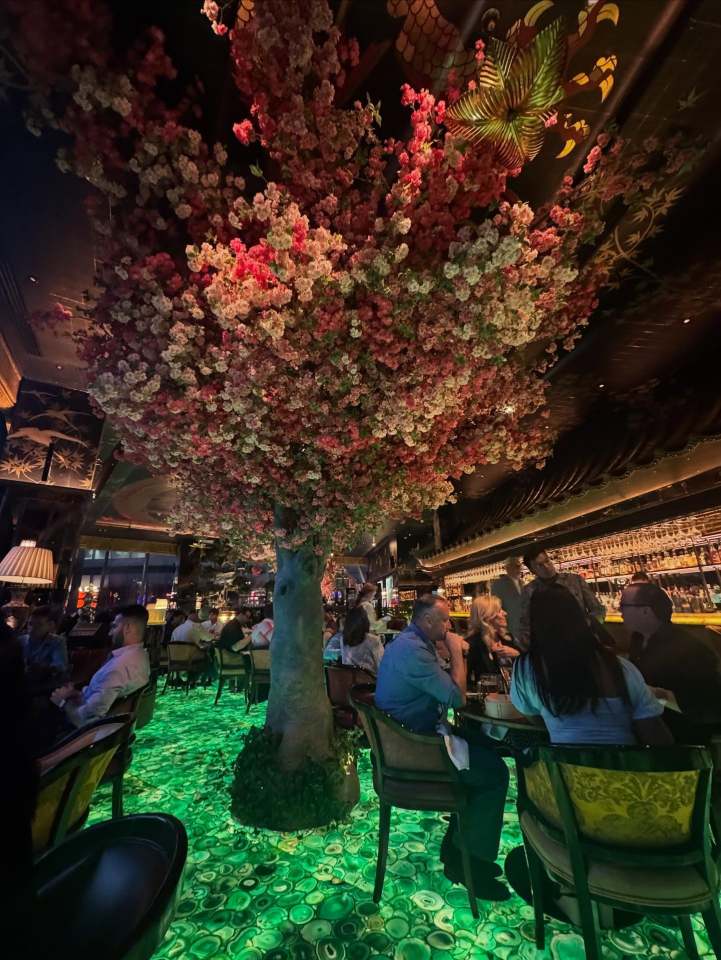 A bar with a large flowering tree overhead and a green agate floor.