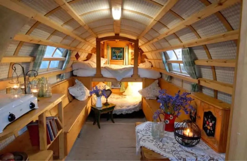 Interior of a wooden camper van with bunks and seating.