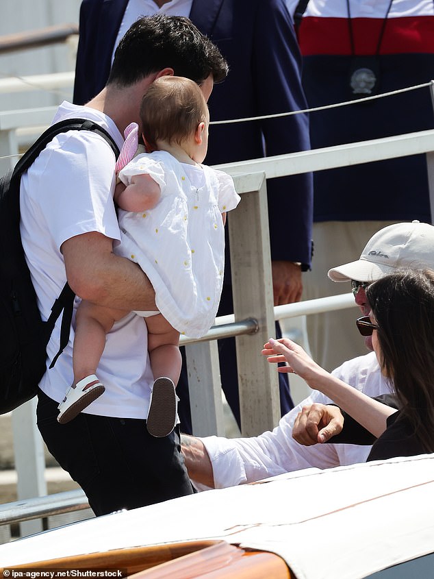 Prince Rajwa Al Hussein holds is daughter as they prepare to head to the Amazon founder's festivities