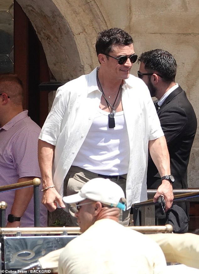 Orlando flashed a wide grin as he climbed in the boat, wearing a button-up shirt left open to reveal a white vest underneath and several pendant necklaces
