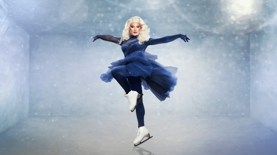 Drag queen ice skating in a blue costume.