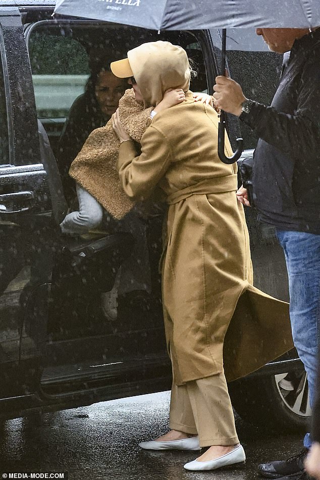 Katy had been delivered to the airport in a black car, where upon her exit from the vehicle muscular bodyguards were waiting with umbrellas