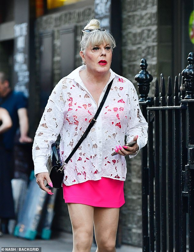 The comedian - who likes to go by the name Suzy but doesn't mind being called by her birth name Eddie - opted for a bright pink mini skirt as she enjoyed a walk in Soho on Monday