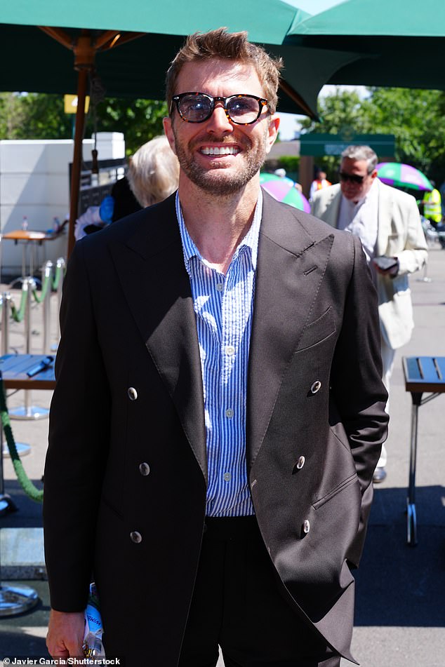 Comedian Joel Dommett wore a black suit and blue and white striped shirt