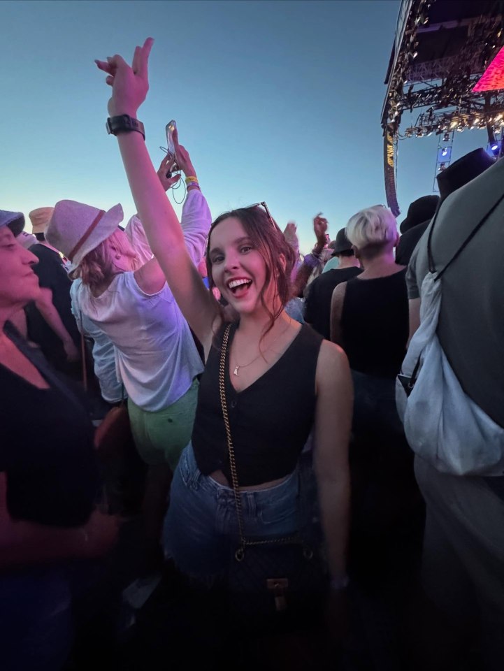 Woman smiling and raising her arm at a concert.