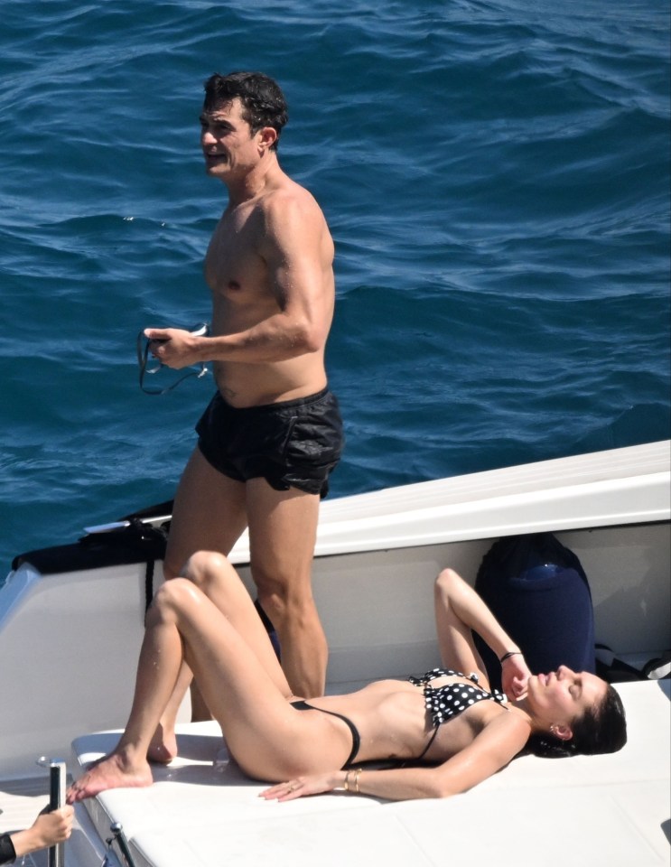 Orlando Bloom on a boat with a woman in a bikini.