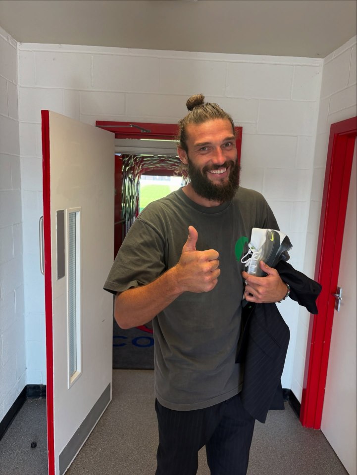 Andy Carroll giving a thumbs up, holding a jacket and shoes.