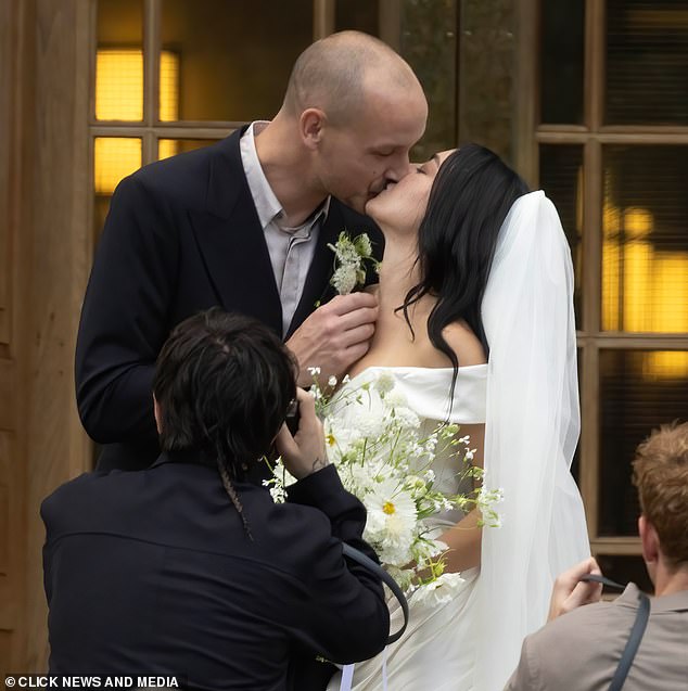 Meanwhile George wore a dark double breasted suit over a light open collared shirt with a flower, that matched his wife's bouquet, in his button hole
