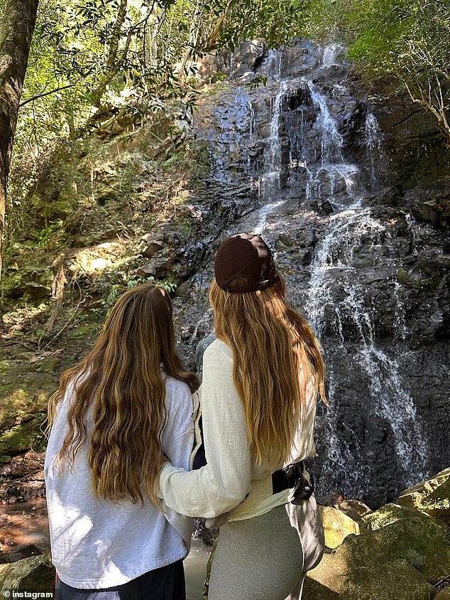 Another photo from Gisele's nature explorations showed her grasping the arm of a young girl, who appeared from behind to be Vivian. They stopped to admire a smaller waterfall tucked away in the trees