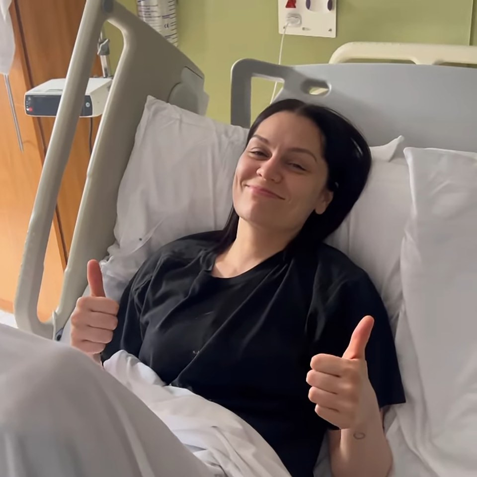 Jessie J giving thumbs up from a hospital bed.